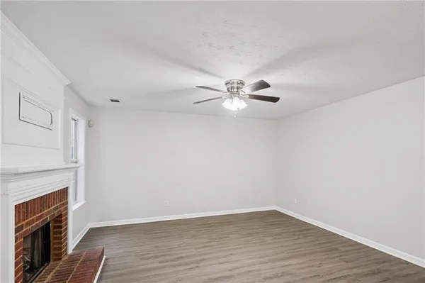 a view of an empty room with wooden floor fireplace and a window