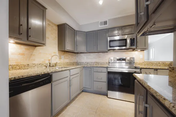 a kitchen with granite countertop a sink dishwasher stove and microwave with wooden cabinets
