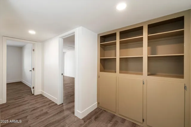 a view of an empty room with wooden floor and closet