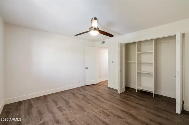 a view of empty room with wooden floor and ceiling fan