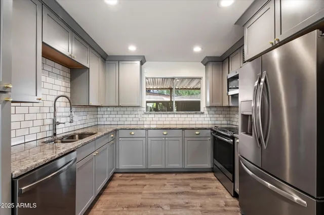 a kitchen with stainless steel appliances granite countertop a sink stove and refrigerator
