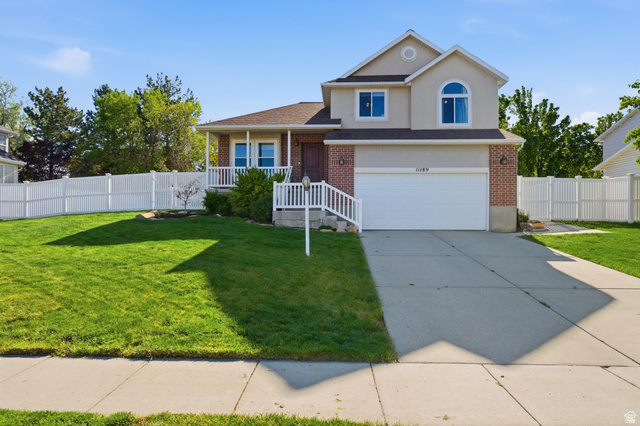 Two-story residence featuring a brick and stucco facade, an attached two-car garage, and a welcoming covered front porch with white railings