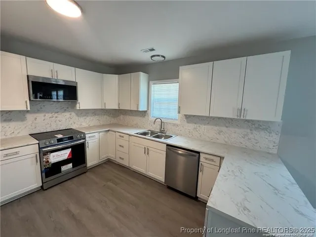 a kitchen with stainless steel appliances granite countertop a stove a sink and a microwave
