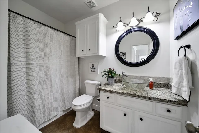 a bathroom with a granite countertop toilet sink and mirror