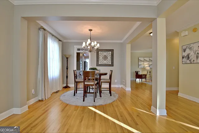 a dining room with wooden floor a chandelier a wooden table and chairs