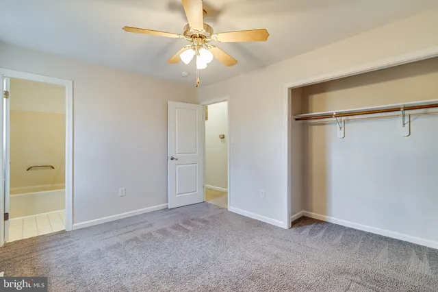 an empty room with closet and a ceiling fan