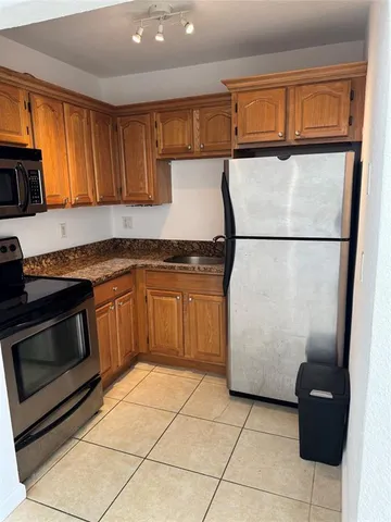 a kitchen with a refrigerator a stove top oven cabinetry a sink and a window