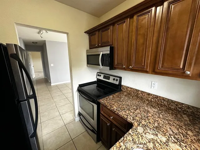 a kitchen with granite countertop a stove refrigerator and microwave