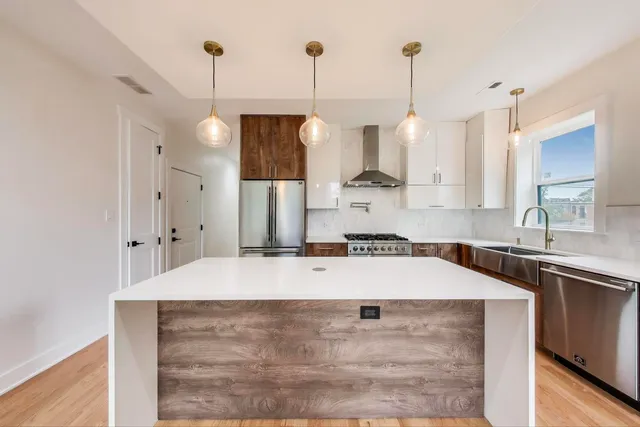 a kitchen with stainless steel appliances granite countertop a sink a refrigerator a stove and white cabinets