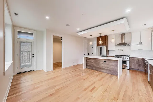 a large kitchen with stainless steel appliances granite countertop a stove and a wooden floors