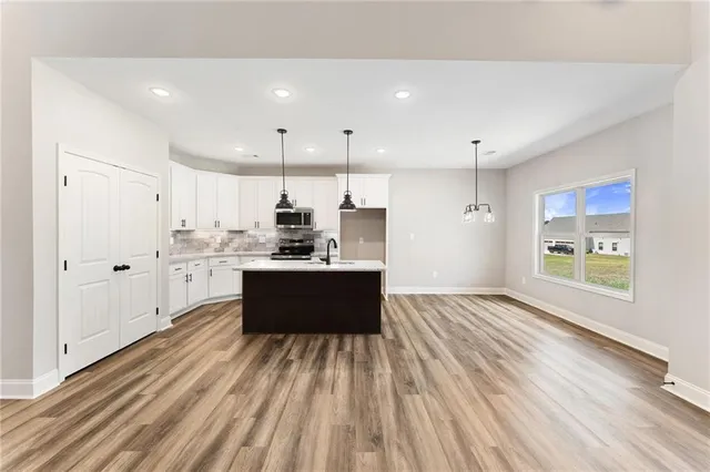 a large white kitchen with kitchen island a sink dishwasher stove with wooden floors