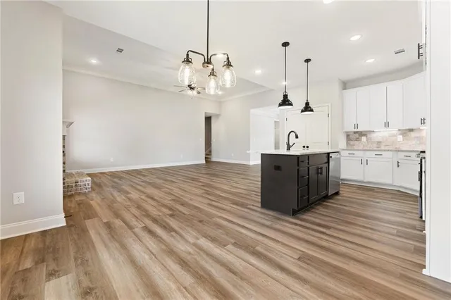 a large room with kitchen island stainless steel appliances a large counter space a sink and a window