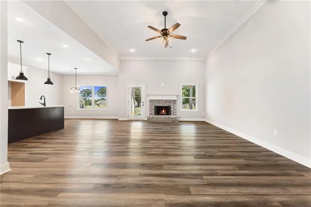 an empty room with wooden floor fireplace and windows
