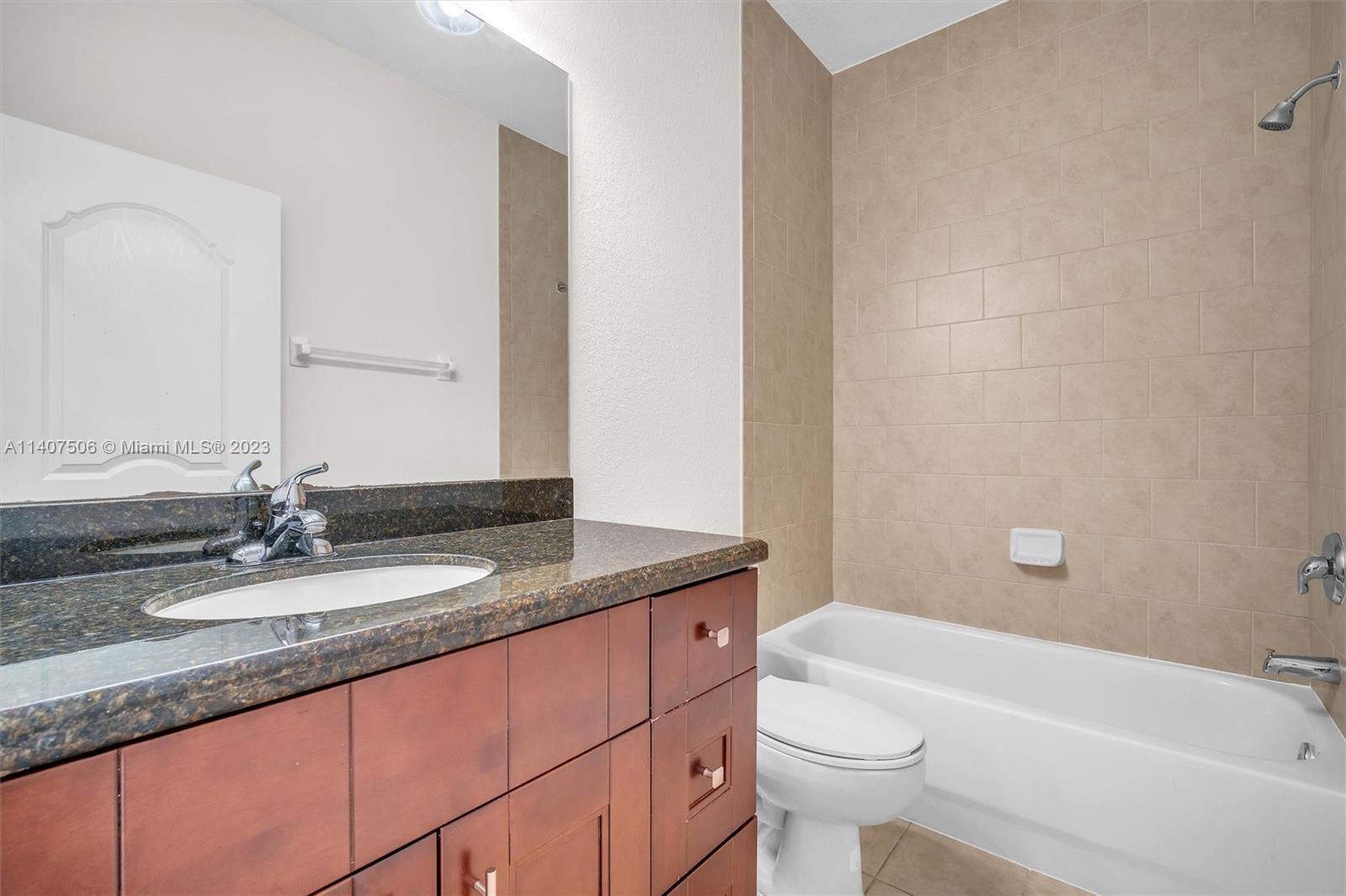 Tamiami Miami, FL 33184 - Photo 36 of 46 a bathroom with a granite countertop sink a toilet a mirror and bathtub