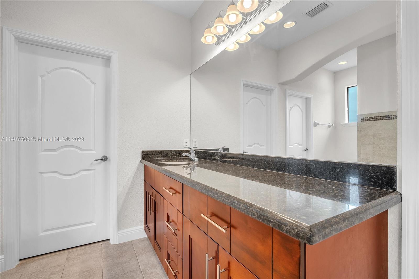 Tamiami Miami, FL 33184 - Photo 37 of 46 a bathroom with a granite countertop sink a mirror and a bathtub
