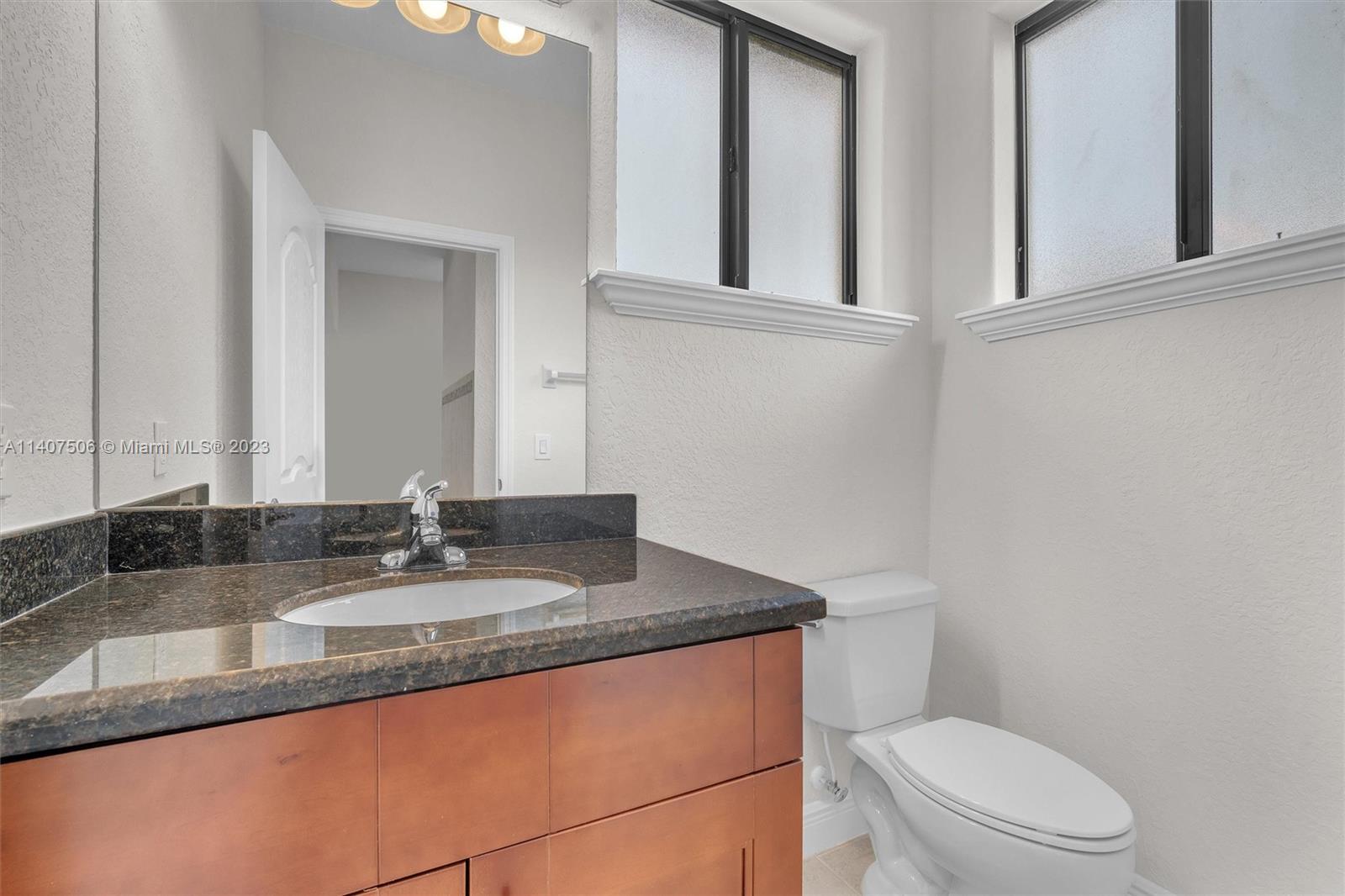 Tamiami Miami, FL 33184 - Photo 10 of 46 a bathroom with a granite countertop toilet sink and mirror