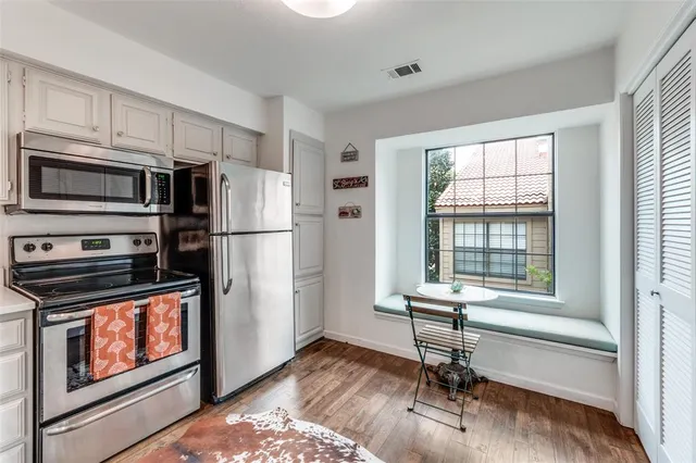 a kitchen with stainless steel appliances a stove a refrigerator cabinets and a dining table