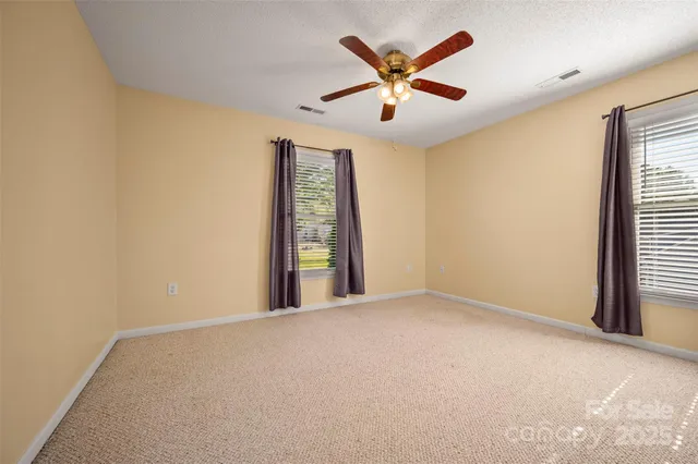 an empty room with window and ceiling fan