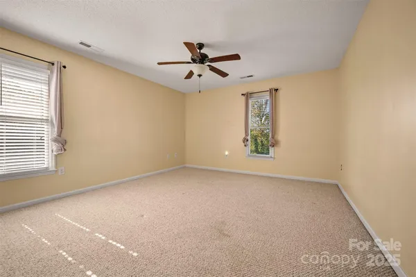 an empty room with windows and fan