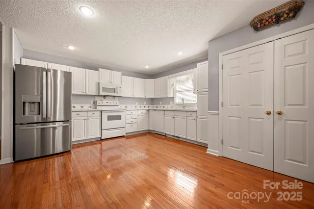 a kitchen with stainless steel appliances granite countertop a refrigerator sink and white cabinets