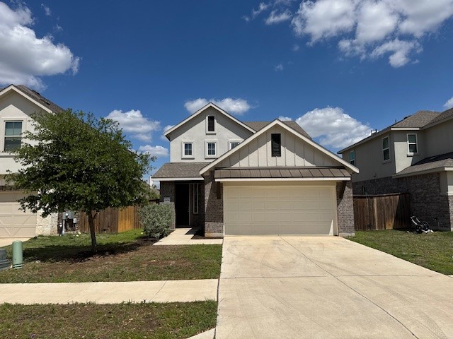 View of front of home featuring board and batten siding, an attached garage, concrete driveway, and brick siding