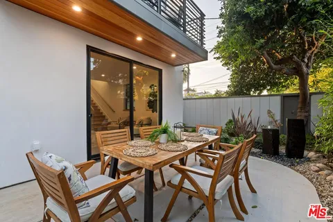 a patio with a table and chairs and potted plants