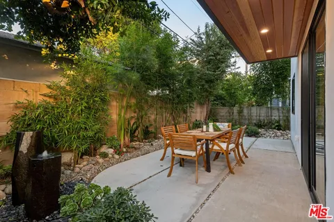 a view of a patio with table and chairs potted plants and floor to ceiling window