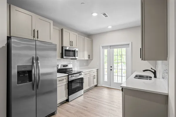 a kitchen with stainless steel appliances granite countertop a refrigerator a sink and white cabinets