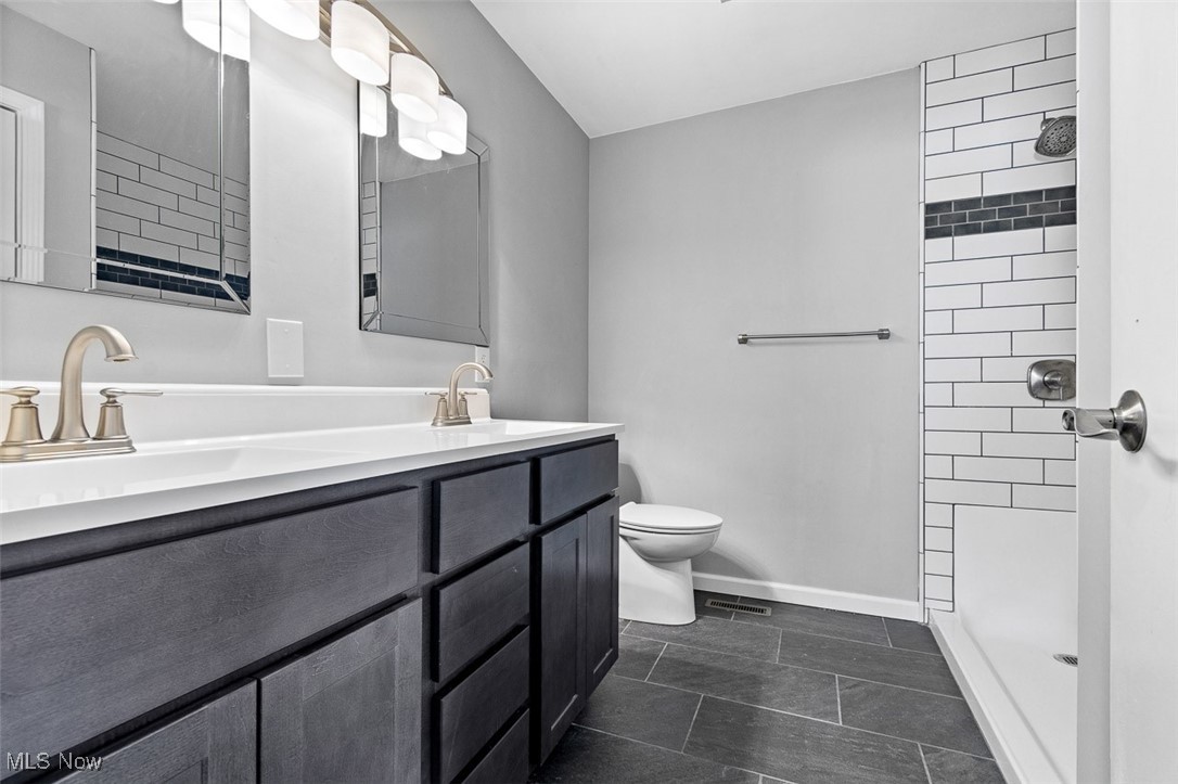 5208 Canaan Center Road Wooster, OH 44691 - Photo 17 of 33 Full bathroom with baseboards, toilet, double vanity, tiled shower, and a sink