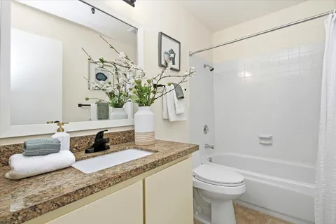 a bathroom with a granite countertop sink a toilet and shower