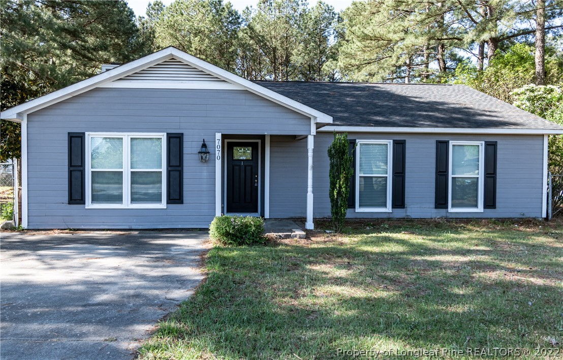 7070 Rockfish Road Raeford, NC 28376 - Photo 1 of 37 a view of a brick house with large windows and a yard