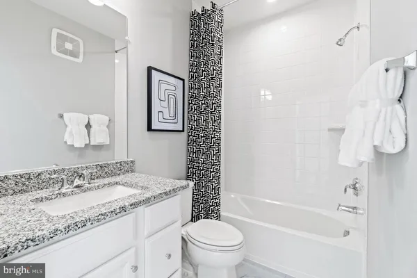 a bathroom with a granite countertop sink a toilet and a bathtub