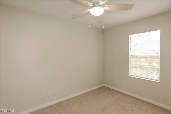 an empty room with a ceiling fan and a window
