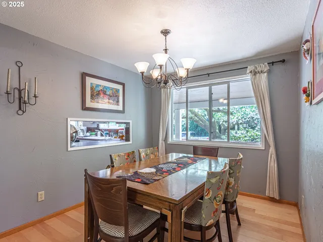 a dining room with wooden floor a chandelier a wooden table and chairs