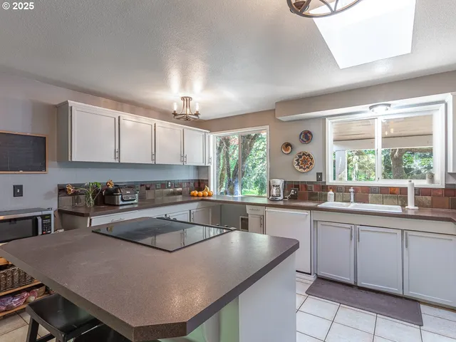 a kitchen with a stove a sink a window and dining table