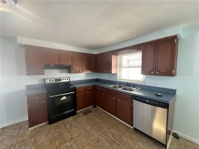 a large kitchen with stainless steel appliances granite countertop a stove a sink dishwasher and a refrigerator
