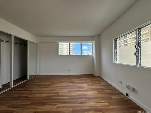 a view of an empty room with wooden floor and a window