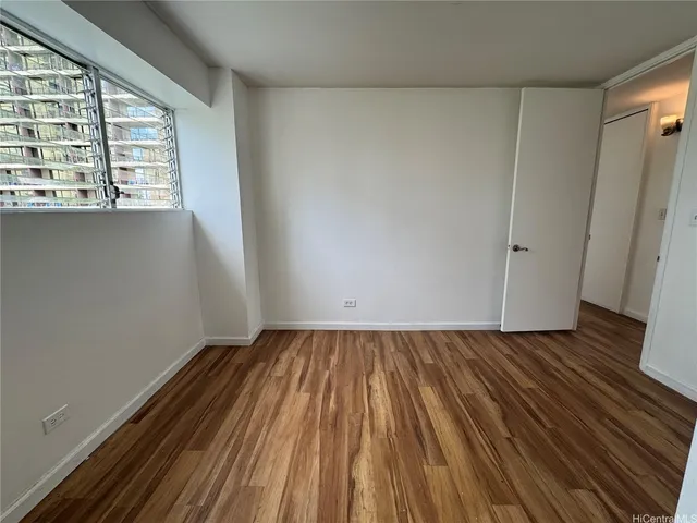 a view of an empty room with wooden floor and a window