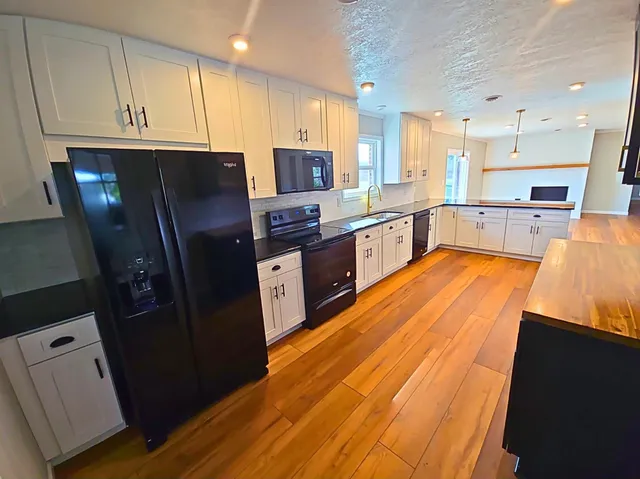 a kitchen with stainless steel appliances granite countertop refrigerator a sink dishwasher and wooden cabinets with wooden floor