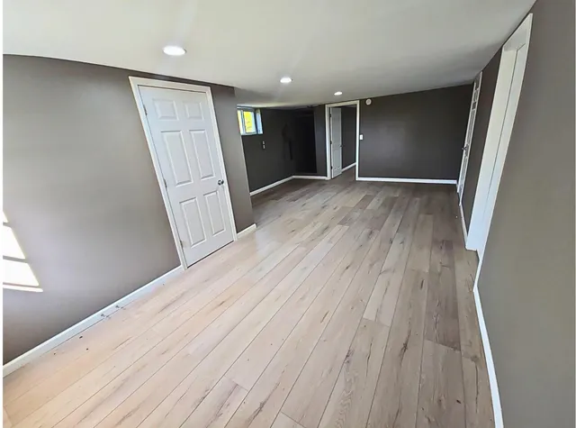a view of an empty room with wooden floor and stairs