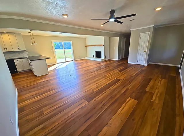a bedroom with wooden floor ceiling fan and window