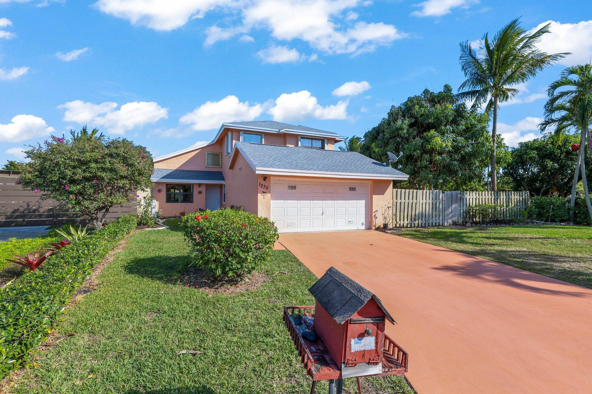 1235 Northwest 19th Terrace Delray Beach, FL 33445 - Photo 4 of 45 a front view of house with yard and trees in the background