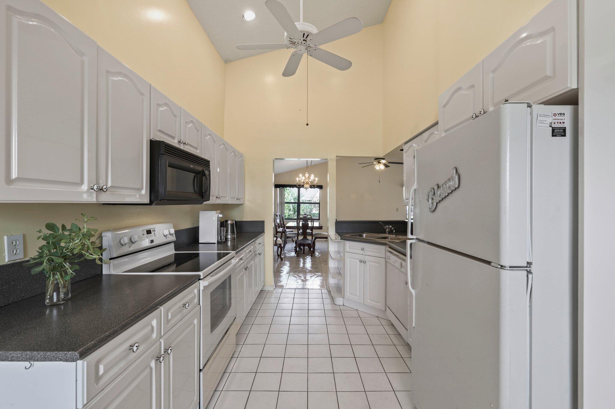 1235 Northwest 19th Terrace Delray Beach, FL 33445 - Photo 6 of 45 a kitchen with granite countertop a refrigerator a sink a stove and cabinets