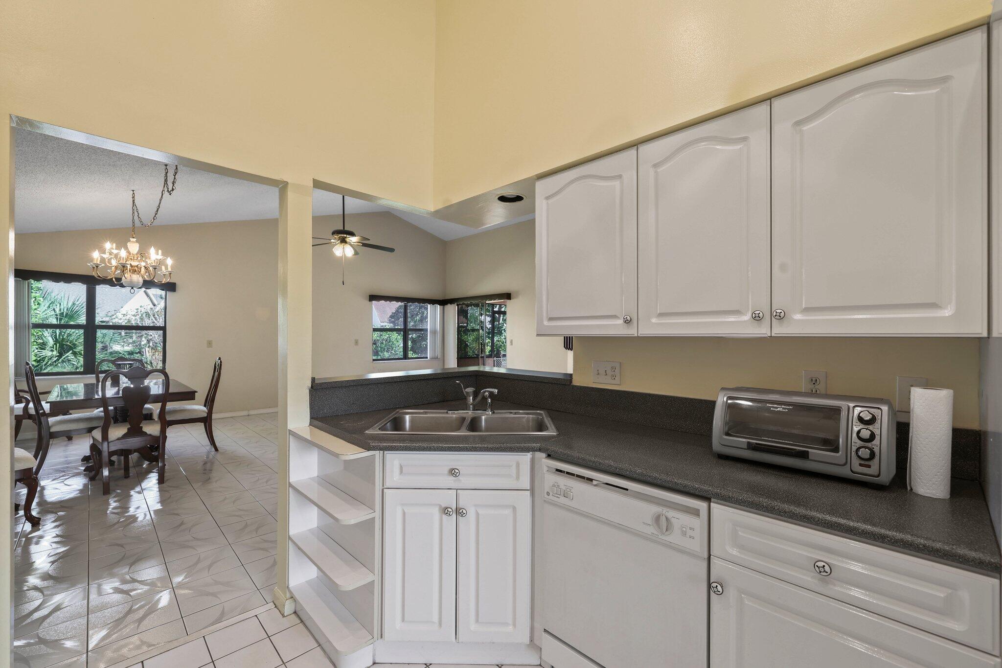 1235 Northwest 19th Terrace Delray Beach, FL 33445 - Photo 8 of 45 a kitchen with granite countertop a sink a stove and cabinets