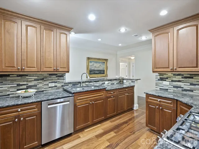 a kitchen with stainless steel appliances granite countertop cabinets sink and wooden floor