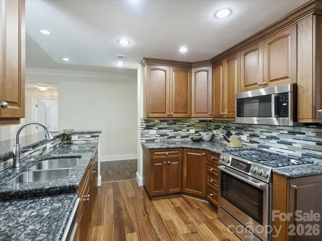 a kitchen with stainless steel appliances granite countertop a sink stove and cabinets
