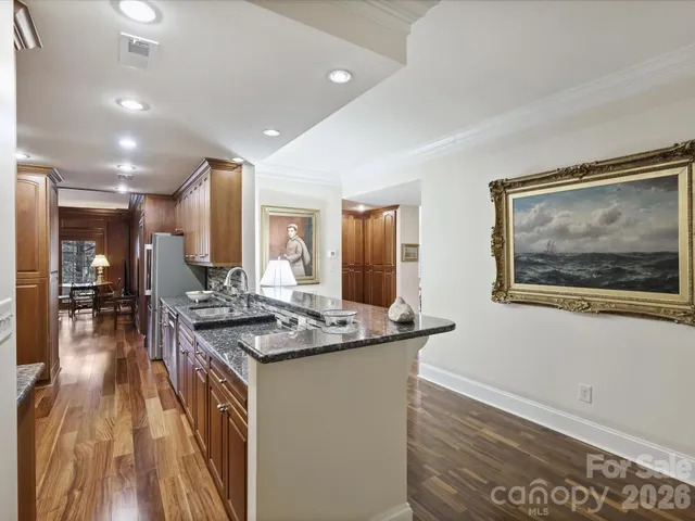 a kitchen with stainless steel appliances granite countertop a stove a sink dishwasher and a refrigerator with wooden floor