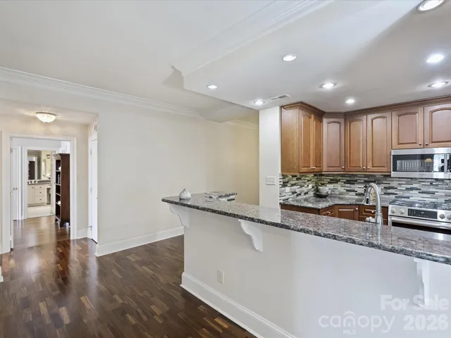 a large kitchen with stainless steel appliances a large counter top a stove and a wooden floors