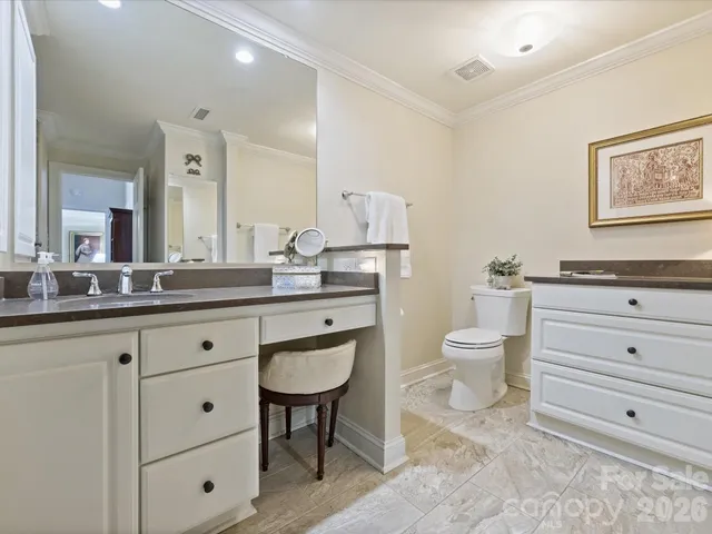a bathroom with a granite countertop toilet a sink and a mirror