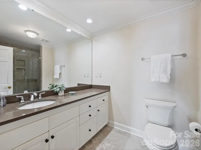 a bathroom with a granite countertop toilet sink and mirror